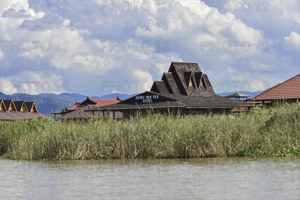 View of a resort with pointed roofs on the banks of a river, Inle Lake, Myanmar, Asia