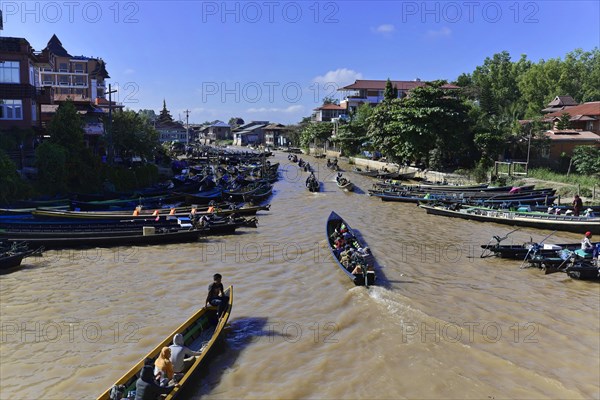 Boats on a river in front of traditional architecture under a blue sky, Pindaya, Inle Lake, Myanmar, Asia