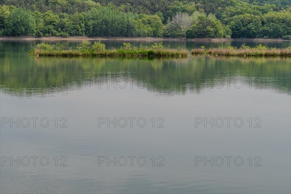 Serene lake with a reflection of the sky and greenery on a cloudy day, in South Korea