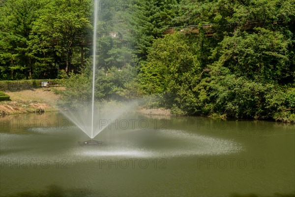 Beautiful water fountain in middle of pond in mountainside wilderness park in Daejeon South Korea