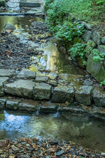 Closeup of shallow man made stream cascading over flat stones on sunny summer day in South Korea