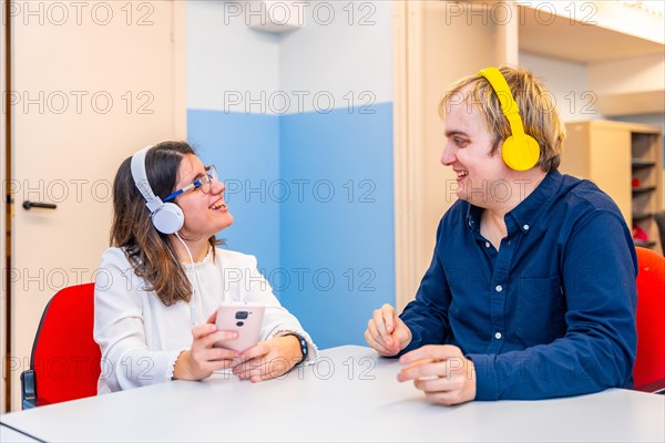 Mental disabled people using phone and listening to music sitting on a leisure room in a center