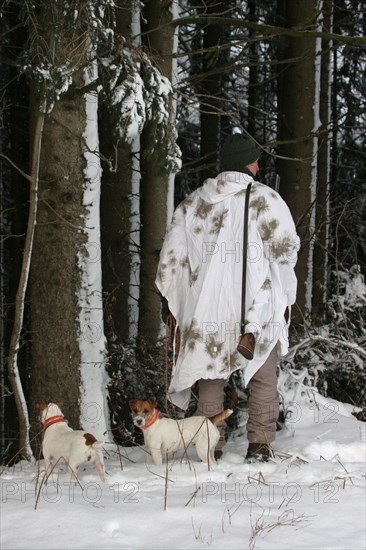 Hunter in winter with snow shirt and hunting dogs Jack Russell Terrier, Allgaeu, Bavaria, Germany, Europe