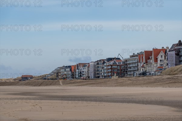 View of a row of buildings along a quiet beach under a cloudy sky, DeHaan, Flanders, Belgium, Europe
