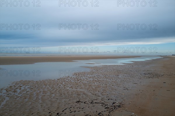Wide beach with puddles of water and sandbanks, covered by a cloudy sky, DeHaan, Flanders, Belgium, Europe