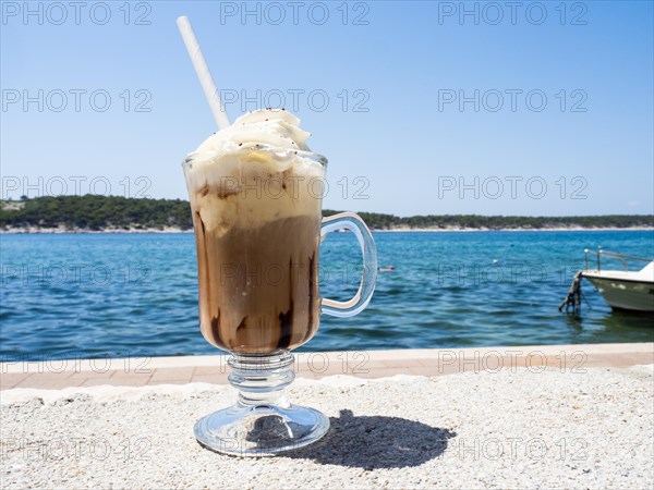 Iced coffee with whipped cream, the sea in the background, Rab Island, Kvarner Gulf Bay, Croatia, Europe