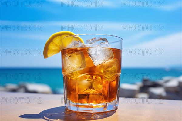 Drinking glass with cocktail, lemon slice and ice cubes with blurry ocean in background. KI generiert, generiert AI generated
