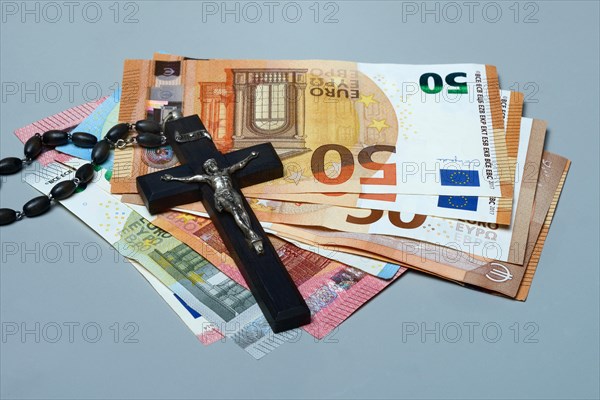 Crucifix and banknotes, church and money, church tax