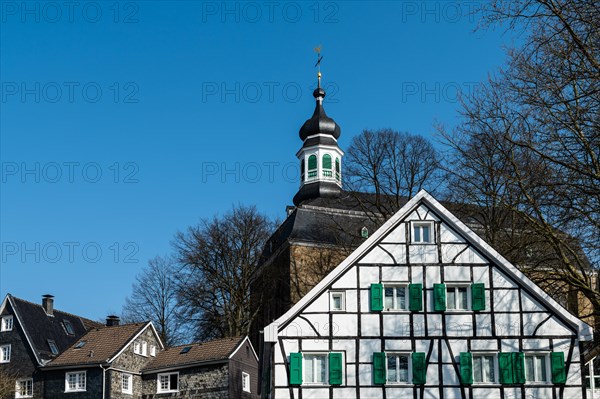 A medieval church behind a classic half-timbered house with a slate-covered roof, Graefrath, Solingen, Bergisches Land, North Rhine-Westphalia