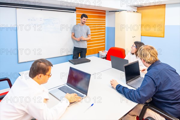 People with special needs attending a IT class using laptop while teacher explain using white board