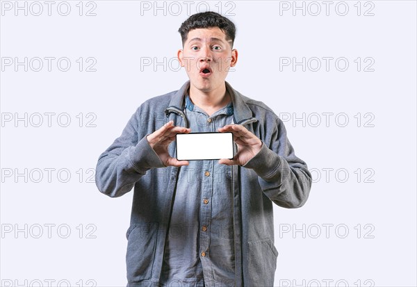 Surprised guy showing cell phone screen isolated. Amazed young man showing an advertisement on screnn cell phone