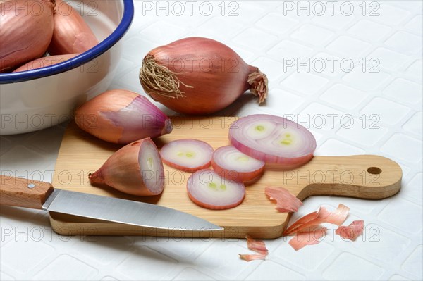 Sliced shallots on a wooden board with a knife, Allium cepa