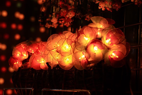 Glowing round paper lanterns on display at a market with soft, warm lighting and bokeh background. Chiang mai, Thailand, Asia