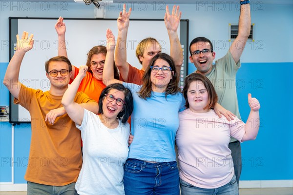 Happy people with special needs posing after gymnastic class laughing at the camera and raising hands