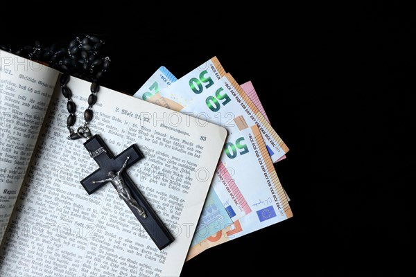 Bible, crucifix and banknotes, church and money, church tax