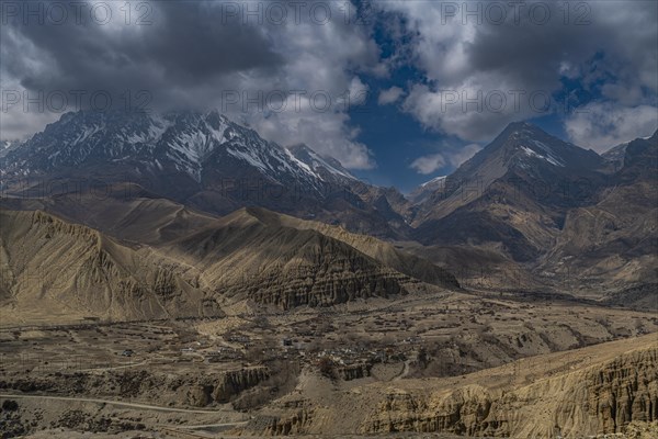 Desert landscape before a snowcapped mountain range, Kingdom of Mustang, Nepal, Asia