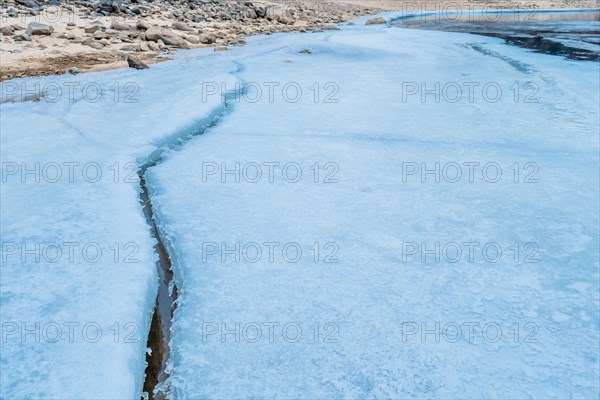 A frozen river with a prominent crack cutting through snow-covered ice, in South Korea