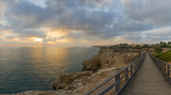 Wooden walkway along the rocky coast in the Algarve, travel, holiday, sunset, evening mood, romantic, summer holiday, Corvoeiro, Portugal, Europe