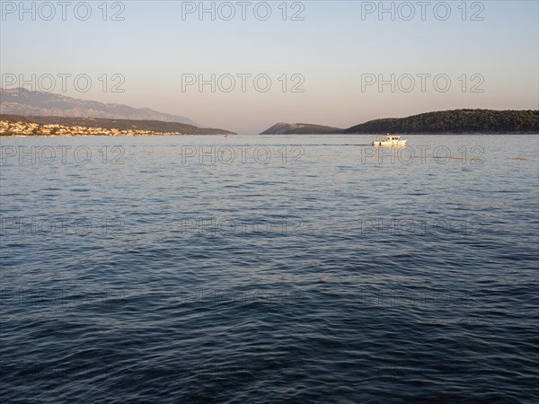 Boat leaving a bay in the evening light, island of Rab, Kvarner Gulf Bay, Croatia, Europe