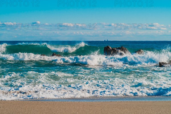 Foamy waves break on rocks with a clear horizon beyond under a deep blue sea, in South Korea