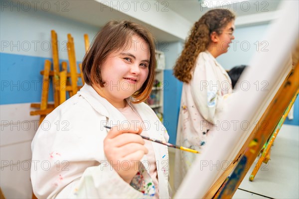 Portrait of a woman with down syndrome in a painting class smiling at camera