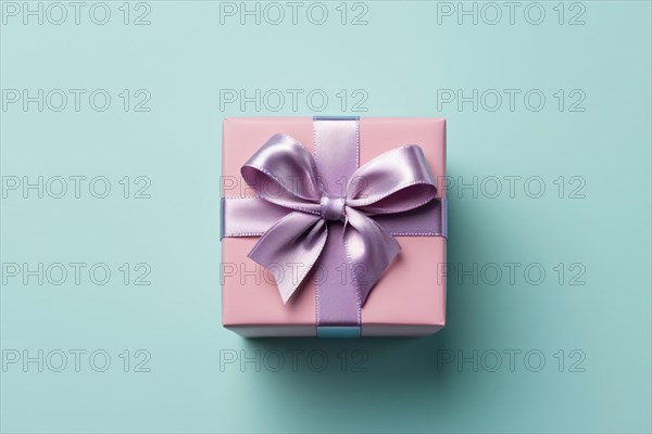 Top view of pink gift box with purple silk ribbon on blue background. KI generiert, generiert AI generated