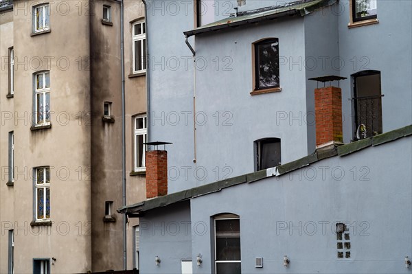 Worn facade of a multi-storey residential building with different windows