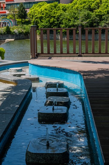 Stepping stones across a water feature beside a modern railing, in South Korea