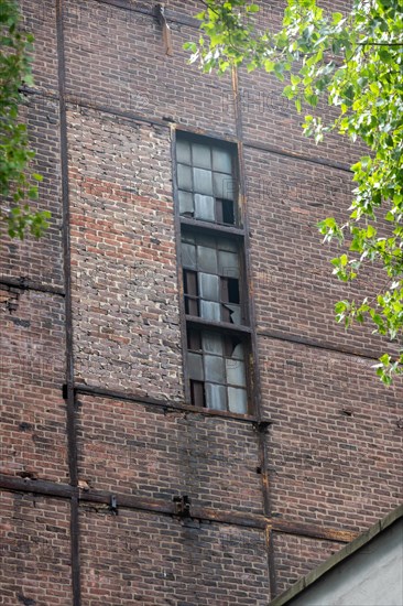 Facade of a dilapidated brick building with long, narrow windows