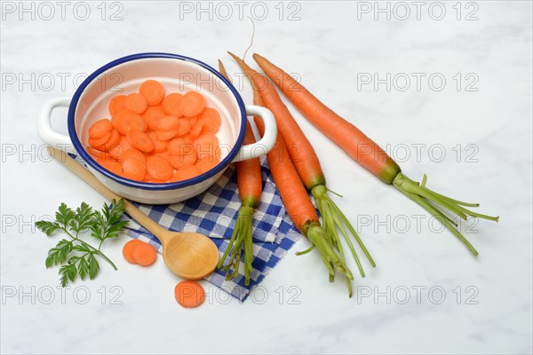 Carrot slices in pot and wooden spoon, carrot (Daucus carota)