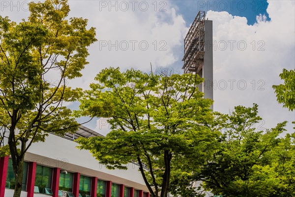 Stadium lights towering over lush trees in an urban setting, in South Korea