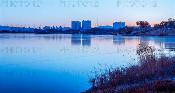 A serene twilight scene over a river with city skyline in the background, in South Korea