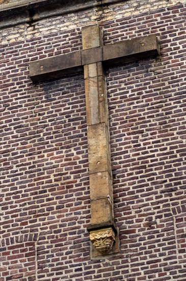 Large stone cross on a brick wall of a church