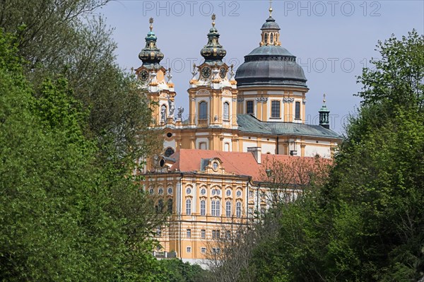 Baroque abbey surrounded by green trees with gold-decorated towers and dome under a blue sky Melk Abbey Wachau Austria