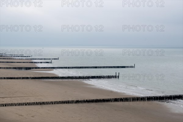 Empty breakwaters jut into the calm sea on a cloudy day