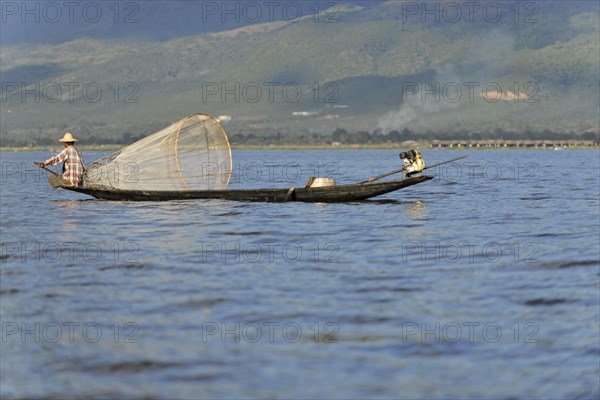 Fisherman enjoying the sun rays while working, surrounded by a mountain landscape, Inle Lake, Myanmar, Asia