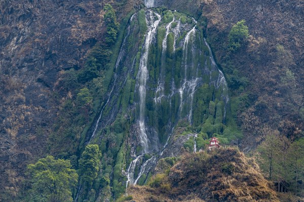 Little stupa undeaneath a huge waterfall, along the highway to Jomsom, Nepal, Asia