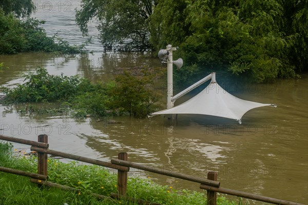 White awning over flooded river where picnic table has been submerged under water from monsoon rains in Daejeon South Korea