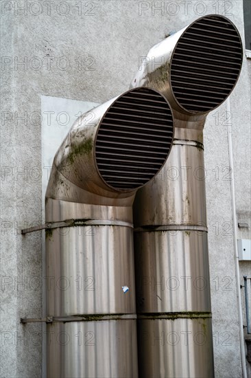 Two large metal, circular ventilation pipes on a building wall