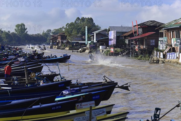 Boats on a moving river with pile dwellings on a sunny day, Inle Lake, Myanmar, Asia