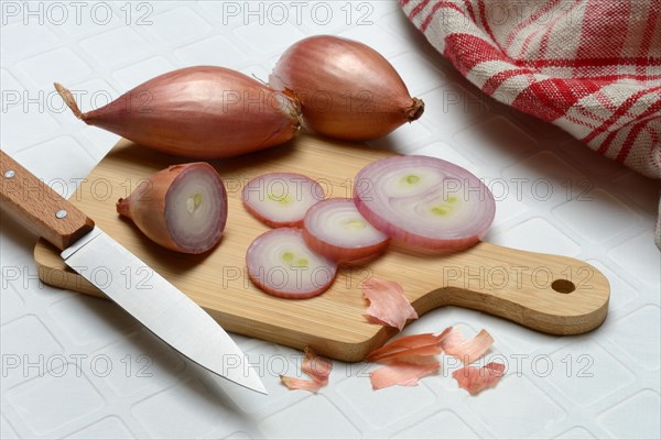 Sliced shallots on a wooden board with a knife, Allium cepa