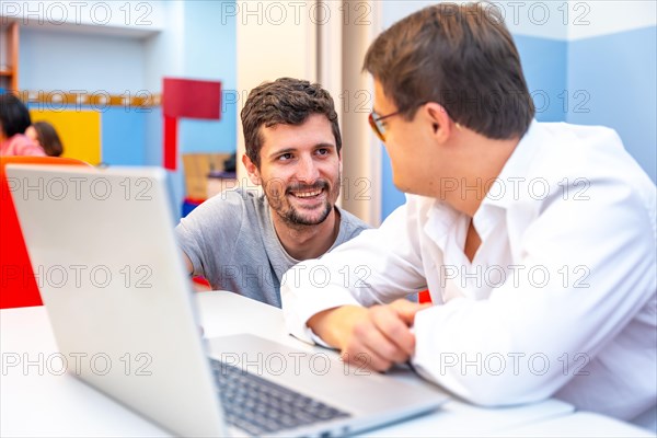 Teacher talking to a man with down syndrome during computing class