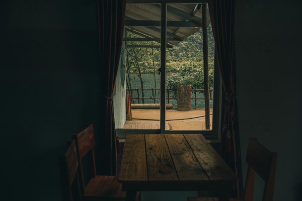 A rustic table by a window opening to a serene lake surrounded by forested hills