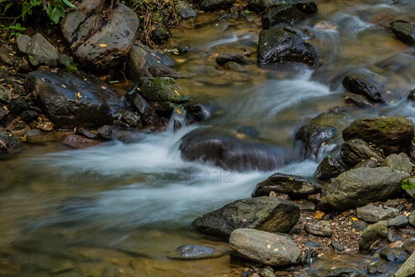Small water fall cascading down rocks in the middle of a small mountain stream in South Korea