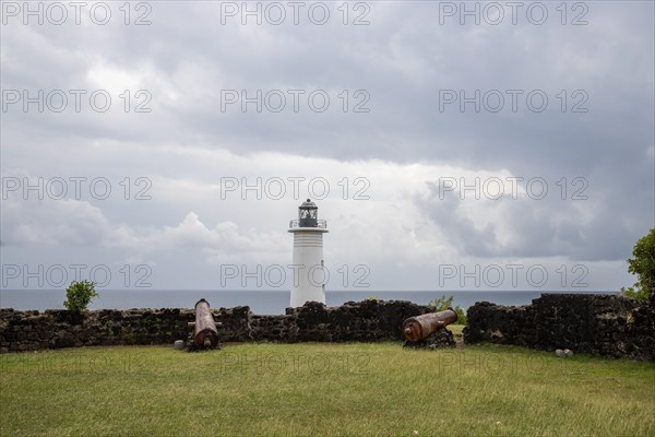 White lighthouse on a steep coast. Dramatic clouds with a view of the sea, pure Caribbean at Le Phare du Vieux-Fort, on Guadeloupe, French Antilles, France, Europe