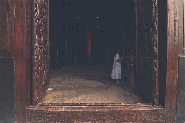 A woman in a white dress in the doorway of Baan Dam Museum or Black House in Chiang rai, Thailand, Asia
