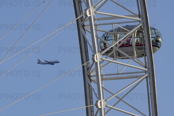 Airbus A319-100 aircraft of British airways in flight behind the pods of the London Eye or Millennium Wheel, London, England, United Kingdom, Europe