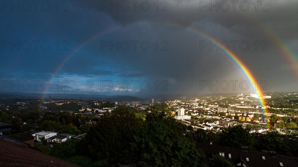 A rainbow stretches over a city with dark clouds and sunny patches, Wuppertal, Bergisches Land, North Rhine-Westphalia