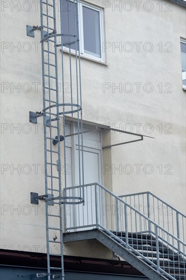 Metal staircase and safety ladder on the facade of an industrial building