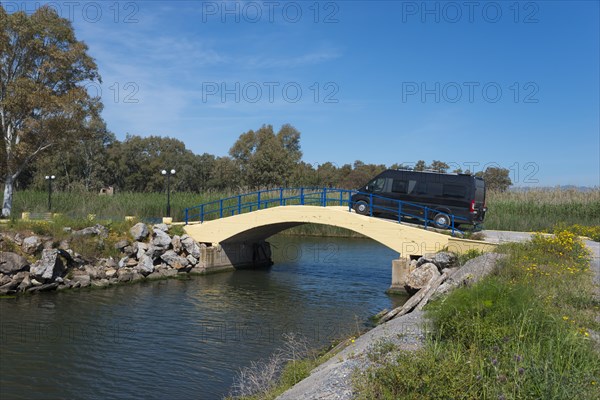 A motorhome drives over a small yellow bridge in a natural landscape on a sunny day, Bouka Beach, Messini, Messinia, Peloponnese, Greece, Europe